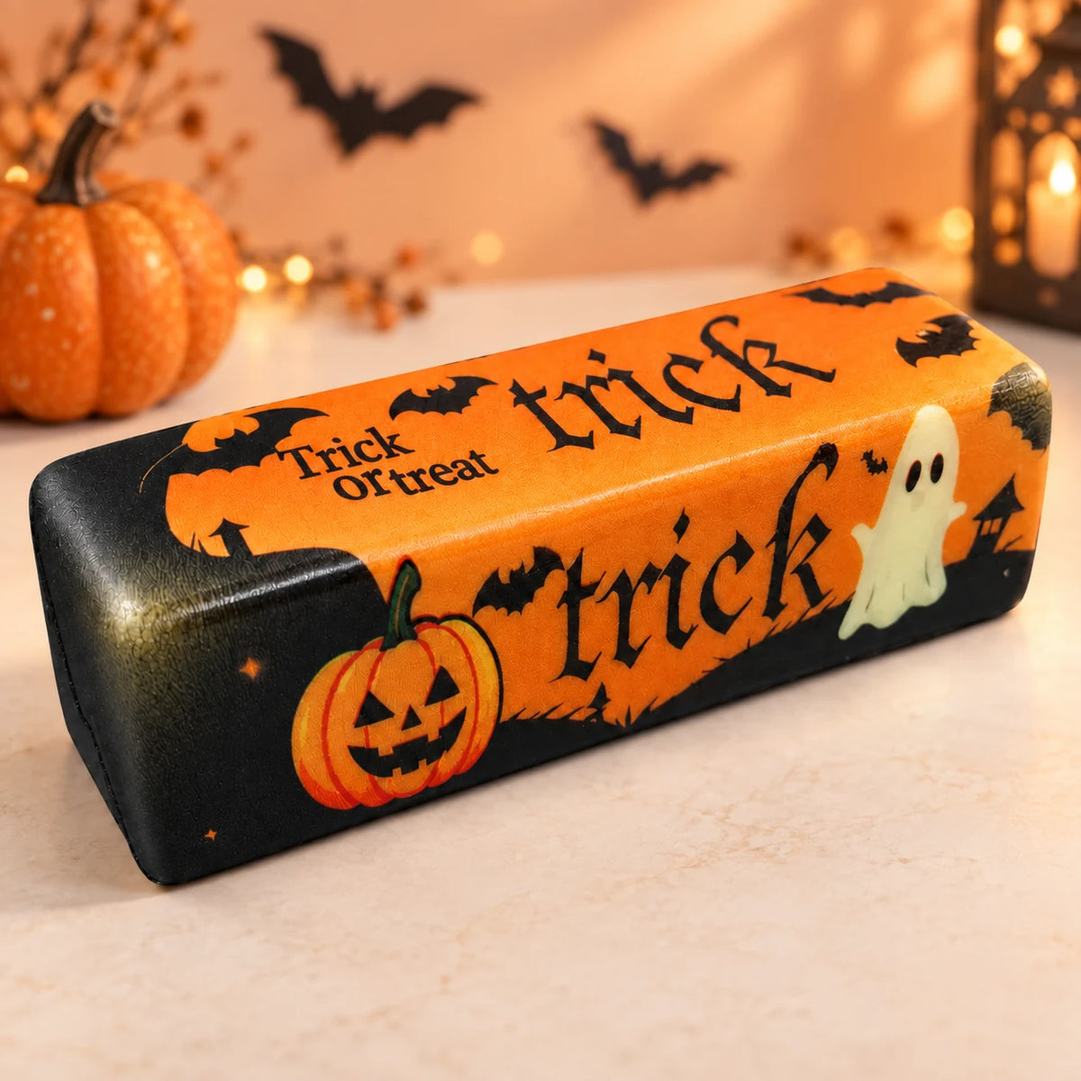 Halloween Butter Squishy dans un décor Halloween avec citrouille et chauves-souris.