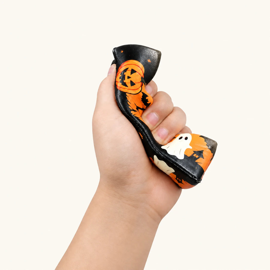 Halloween Butter Squishy comprimé dans une main, montrant la déformation du produit.